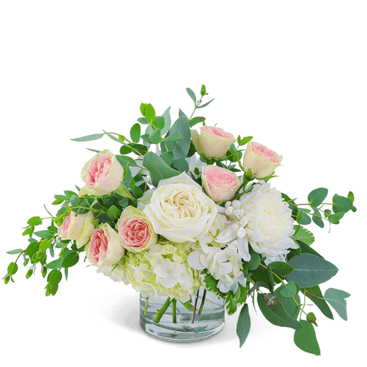 Awaken the senses as you walk into your own romantic floral fantasy! Traditional roses, contemporary mums, and playful hydrangea mix to create a stunning bouquet! Blushing Beauty is bursting with blossoms and arranged in an eye-catching clear glass vase, accented with premium foliage. A shop favorite, this timeless beauty is perfect for any occasion! 